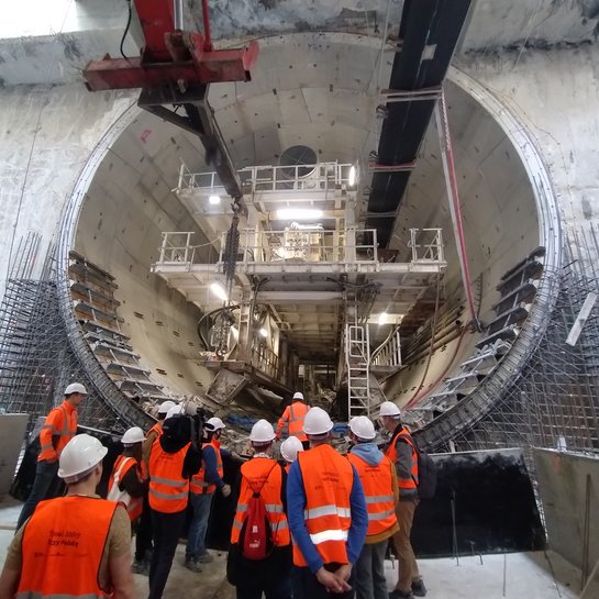 Uczestnicy wycieczki po podziemnym tunelu kolejowym w Łodzi obserwują tarczę TBM; fot. Rafał Wilgusiak