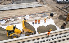 Widok z góry na budowę tunelu kolejowo-drogowego w Sulejówku, widać wykonawców i wywrotkę wysypującą ziemię, fot. Anna Hampel