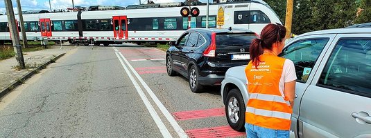 Koordynator kampanii podczas akcji ulotkowej, przejazd kolejowy, pociąg na torach