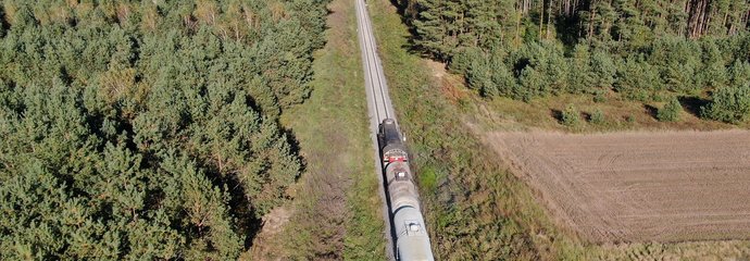 Pociąg towarowy jedzie przez las, fot. Artur Lewandowski PKP Polskie Linie Kolejowe SA