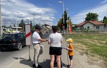 Przedstawiciel PLK SA wręcza ulotki kobiecie i chłopczykowi na chodniku przed przejazdem kolejowo-drogowym; fot. Anna Znajewska-Pawluk
