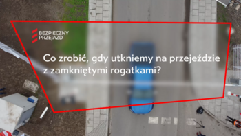 Ujęcie z filmu, widok kamery z góry na samochód, tekst Co zrobić gdy utkniemy na przejeździe. 