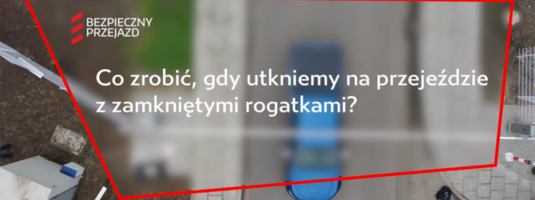 Ujęcie z filmu, widok kamery z góry na samochód, tekst Co zrobić gdy utkniemy na przejeździe. 