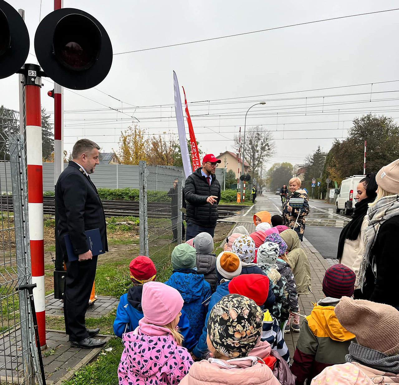 Przedstawiciele kampanii obok przejazdu kolejowo-drogowego tłumaczą przedszkolakom przepisy bezpieczeństwa